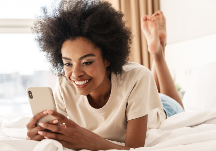 woman on bed looking at phone smiling Good Morning Texts for Her