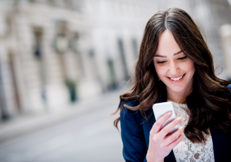 woman outdoors looking a phone smiling Good Morning Texts for Her