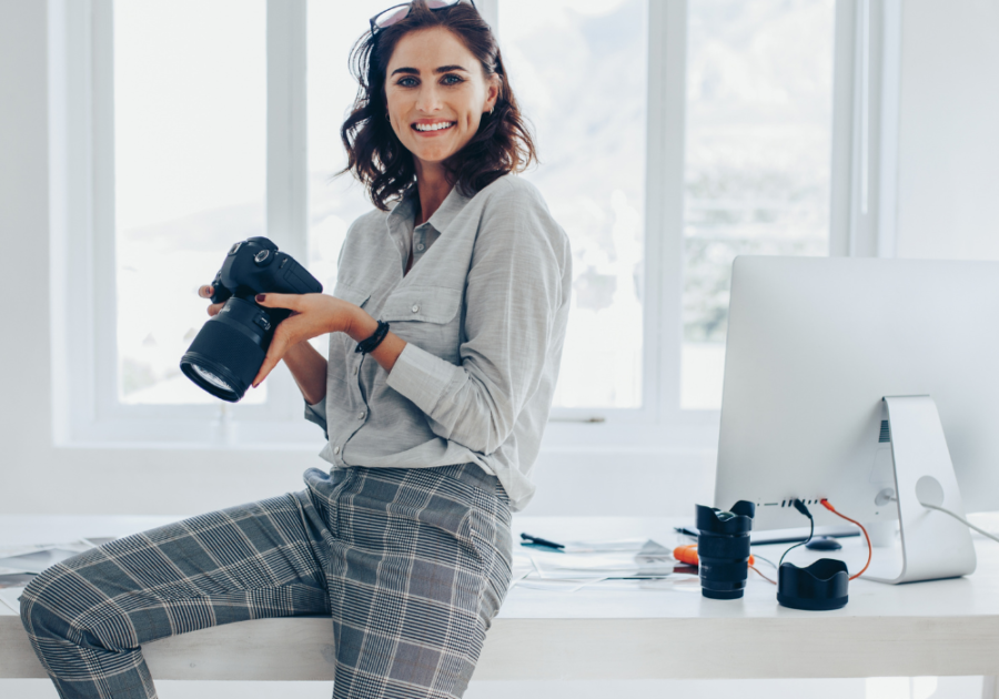 woman holding camera sitting on desk high-value woman