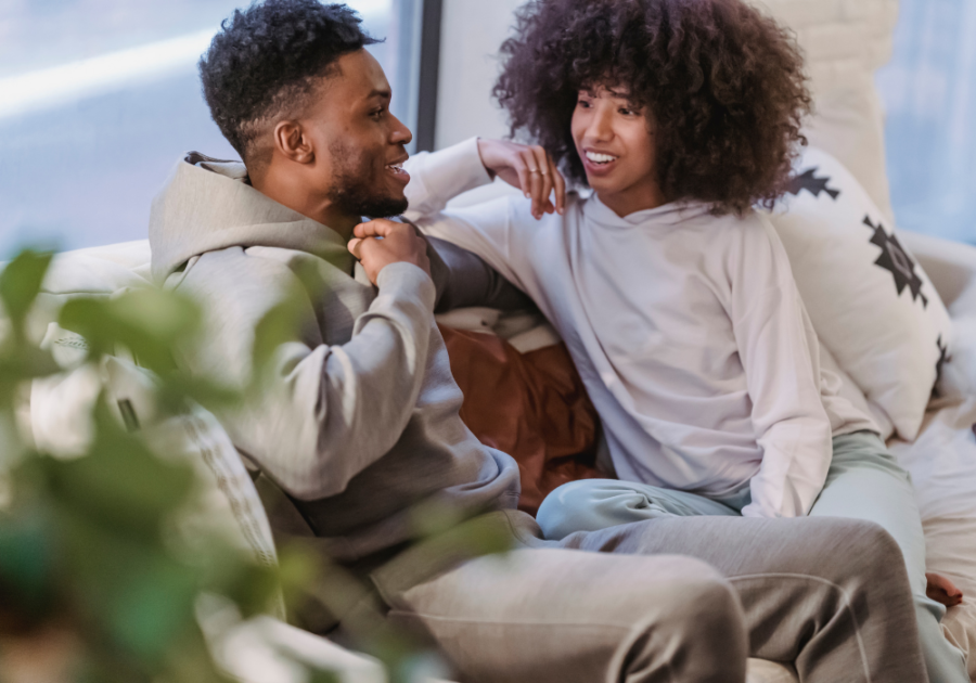 couple smiling sitting on sofa Tough Relationship Questions