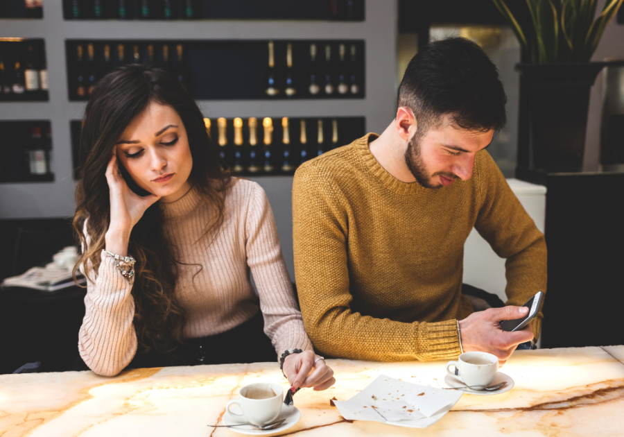 couple sitting in coffee shop ignoring each other Reasons Guys Don't Like You