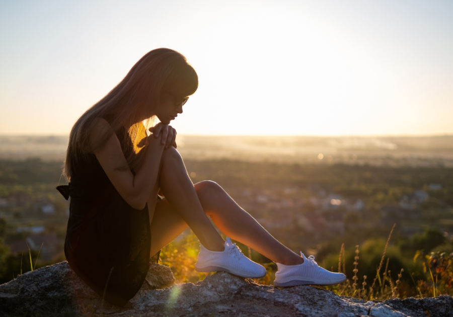 woman sitting on rock at sunset introvert or extrovert quiz