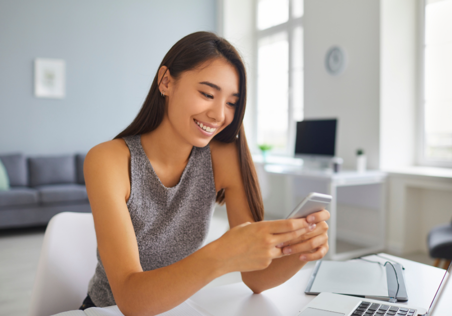 woman smiling looking at phone Fun Questions to Ask Your Boyfriend 