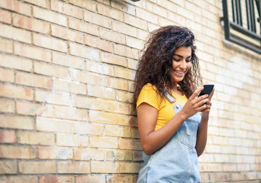 woman standing by wall laughing Funny Jokes To Tell Your Friends