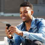 man smiling looking at phone Interesting Questions to Ask a Girl Over Text 