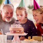 older couple sitting with child with birthday cake Birthday Wishes for Your Granddaughter