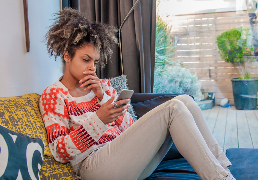 woman looking at phone sitting on sofa Why Did My Ex Block Me