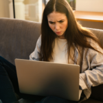 woman on sofa looking on laptop Why Did My Ex Block Me