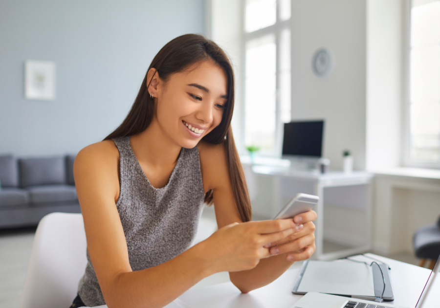 woman looking at phone smiling Cute Things to Say to Your Crush