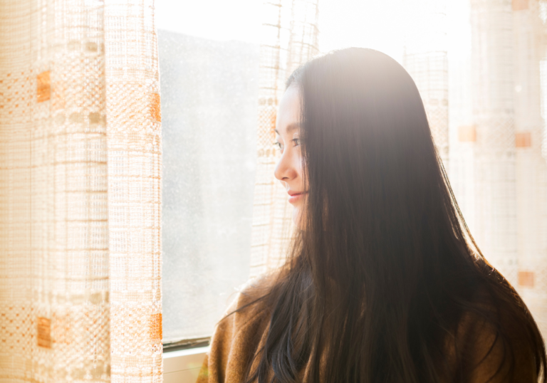 woman standing alone indoors signs you're healing from a breakup