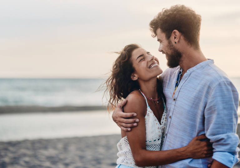 couple at ocean hugging smiling what do men find attractive in women